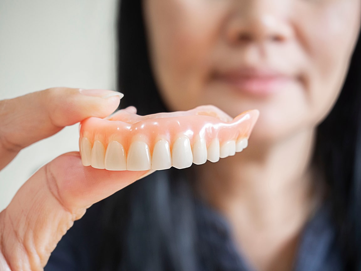 woman holding up dentures in Westerville, OH